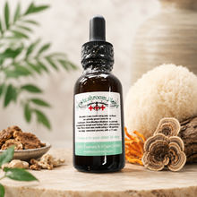 Load image into Gallery viewer, An amber glass dropper bottle labeled 'Mushroom Magic' stands on a wooden surface with herbal props, including sliced mushrooms, dried roots, and a white sponge, against a softly blurred warm background.