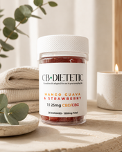 Load image into Gallery viewer, A bottle of CB DIETETIC CBD gummies in Mango Guava &amp; Strawberry flavor, styled on a stone surface with a lit candle, folded blanket, and eucalyptus leaves in a warm, cozy setting.