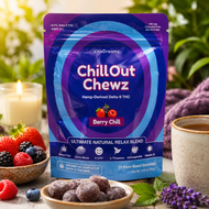 A stand-up pouch of VitaDreamz Chill Out Chewz Berry Chill gummies is displayed in a styled setting with fresh berries, a cup of tea, and lavender flowers. The packaging is predominantly purple and blue with white text.