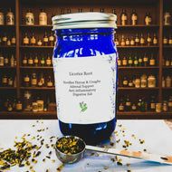 Blue jar of licorice root with a spoonful of dried licorice on a patterned background