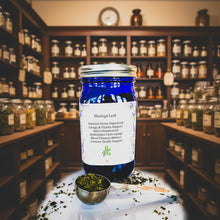 Load image into Gallery viewer, Blue jar labeled 'Moringa Leaf' with a spoonful of moringa leaves on a patterned background