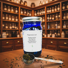 Load image into Gallery viewer, Blue jar of peppermint leaf with a label and a spoonful of leaves on a patterned background