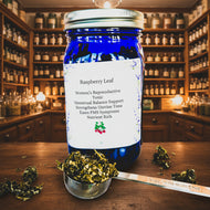 Blue jar labeled 'Raspberry Leaf' with a spoonful of dried herbs on a patterned background
