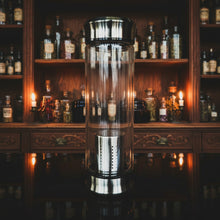 Load image into Gallery viewer, Glass container with metallic top and bottom on a dark surface with a patterned background